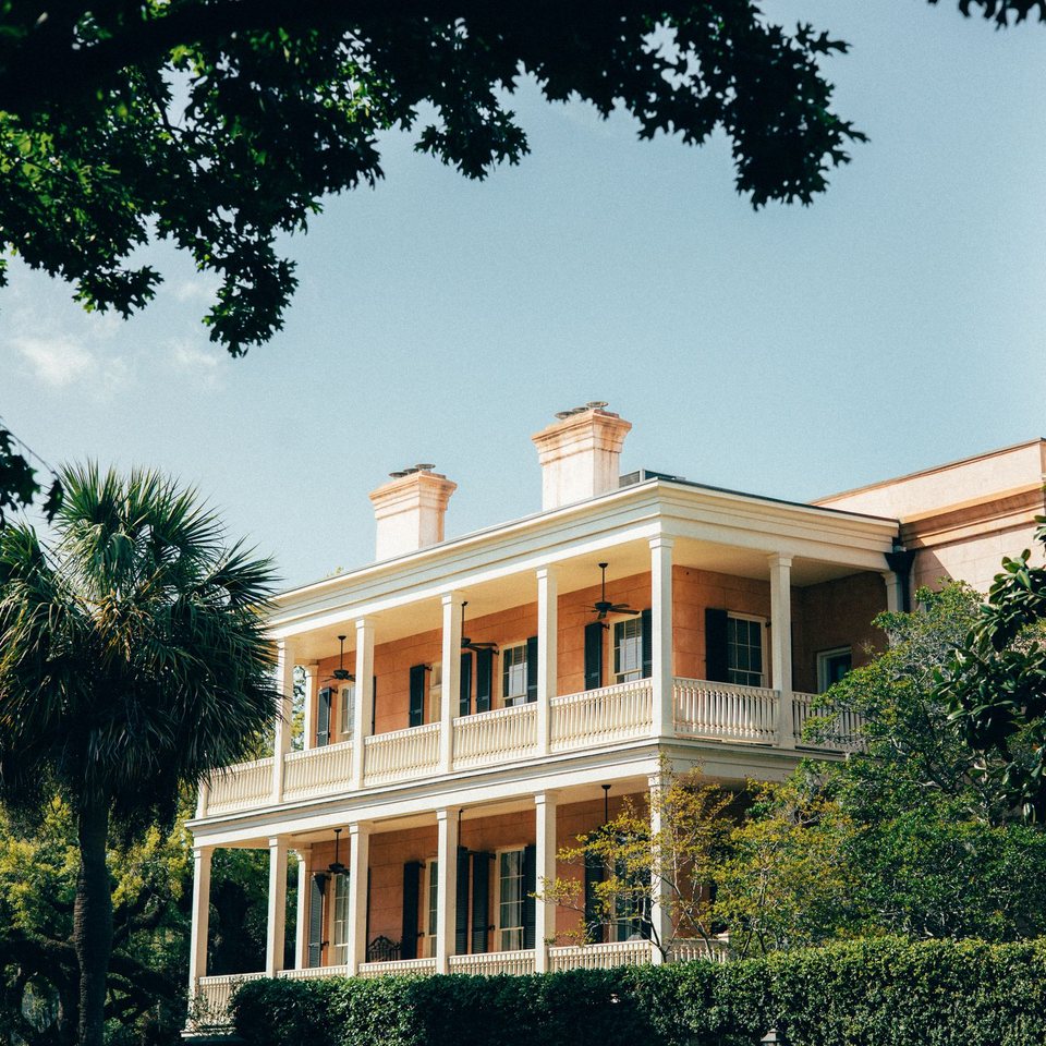 A Southern home with wide double porches, a palmetto tree and live oaks